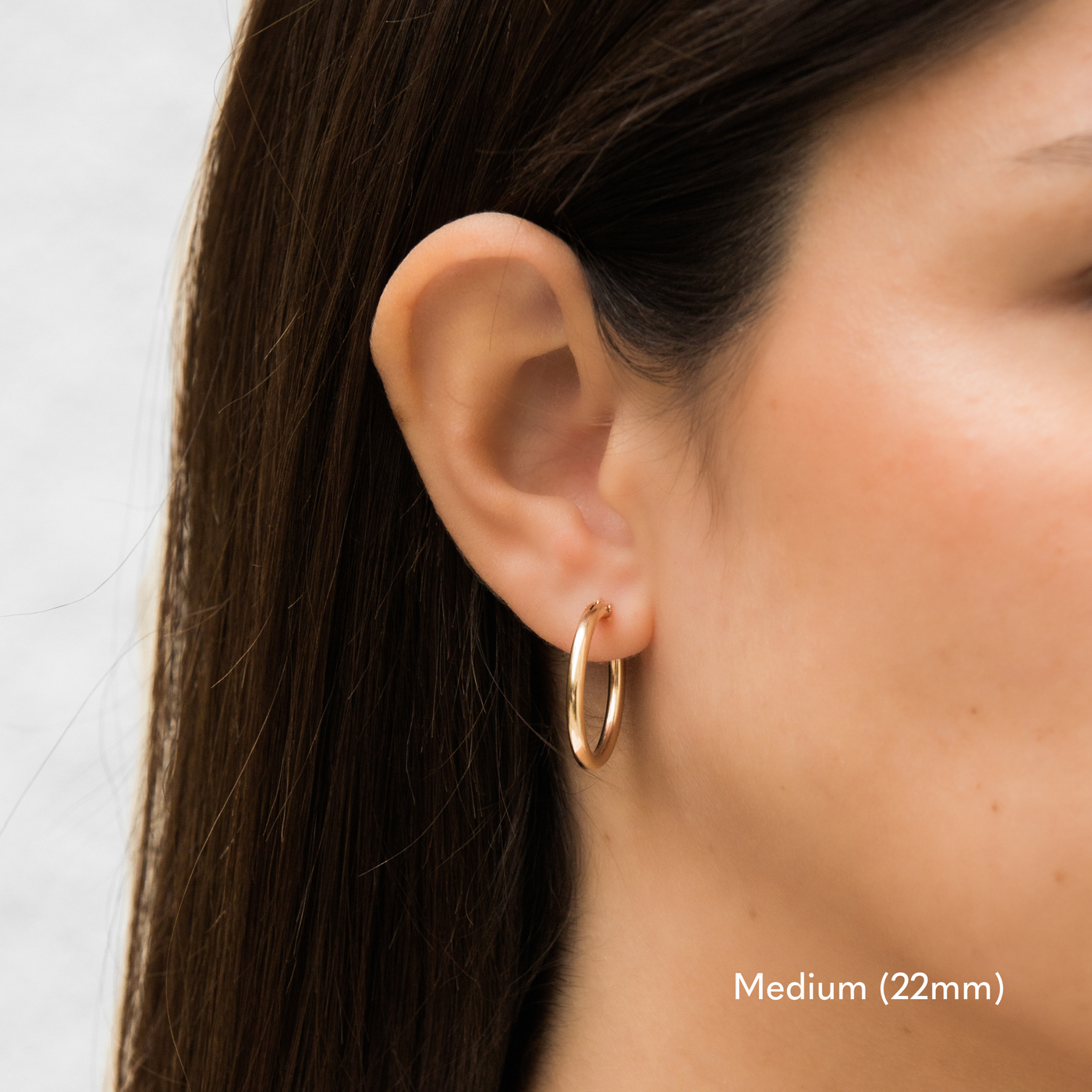 Woman wearing a single medium 22mm gold Everyday Hoop Earring on one ear. The photo is taken from the side, showing her earring, and hair pulled back.

Medium (22mm) Everyday Hoop Earrings by Simple & Dainty Jewelry