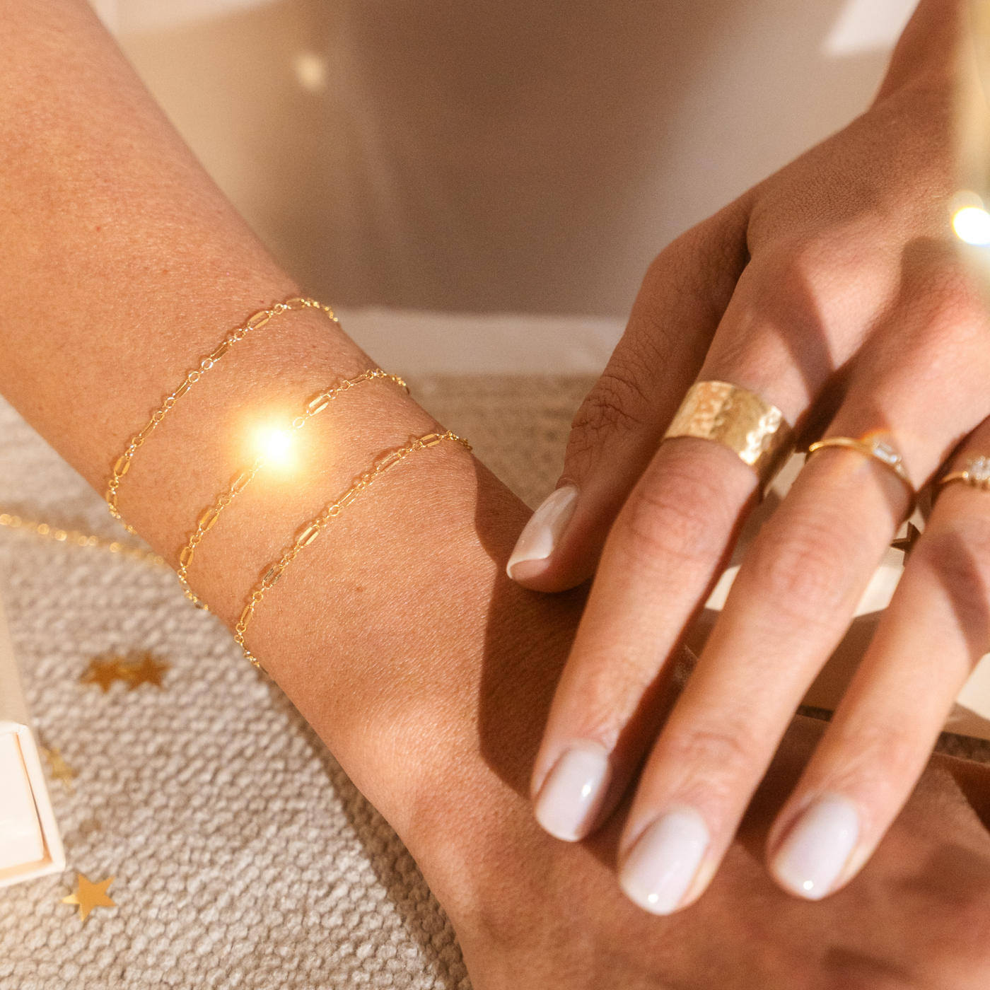Close-up of a hand wearing gold jewelry on a neutral background