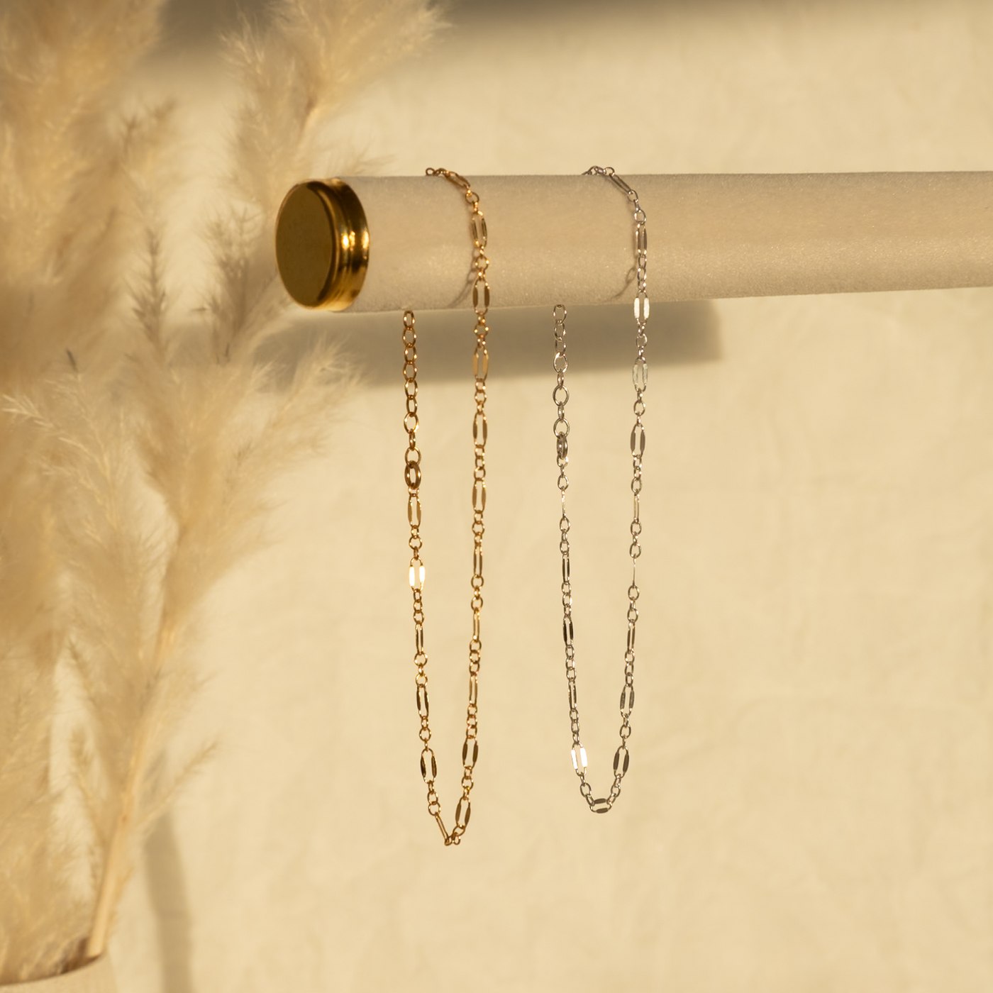 gold and silver chain bracelets on a beige background