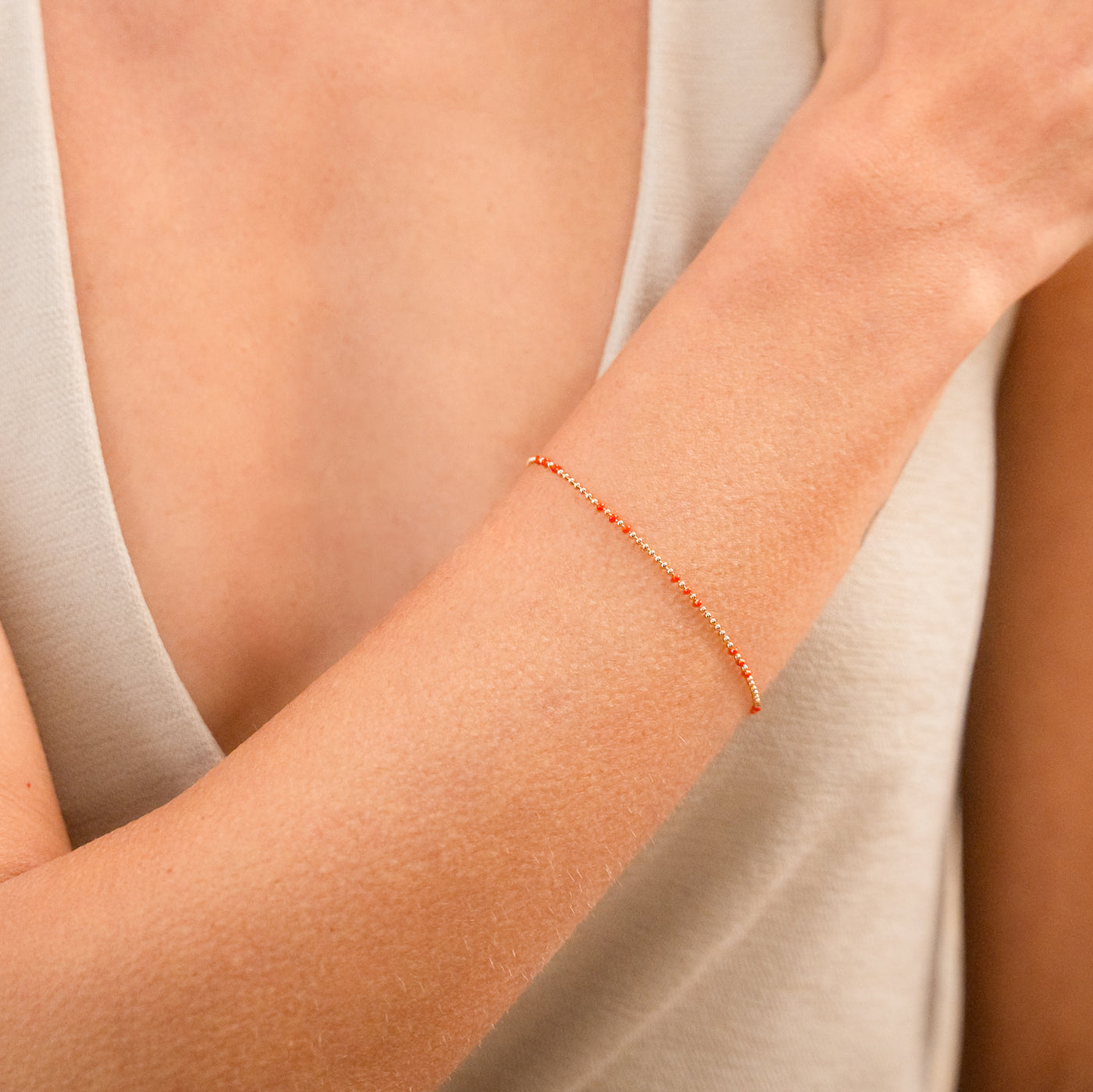 Close-up of a woman's wrist wearing the Red Enamel Ball Chain Bracelet.