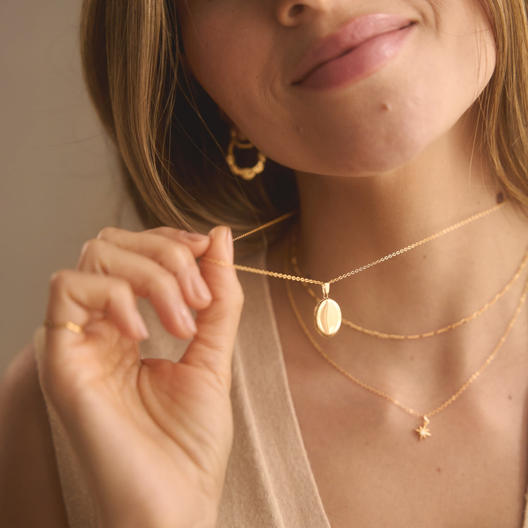 Gold necklaces on a white surface next to a sheet of dog stickers.