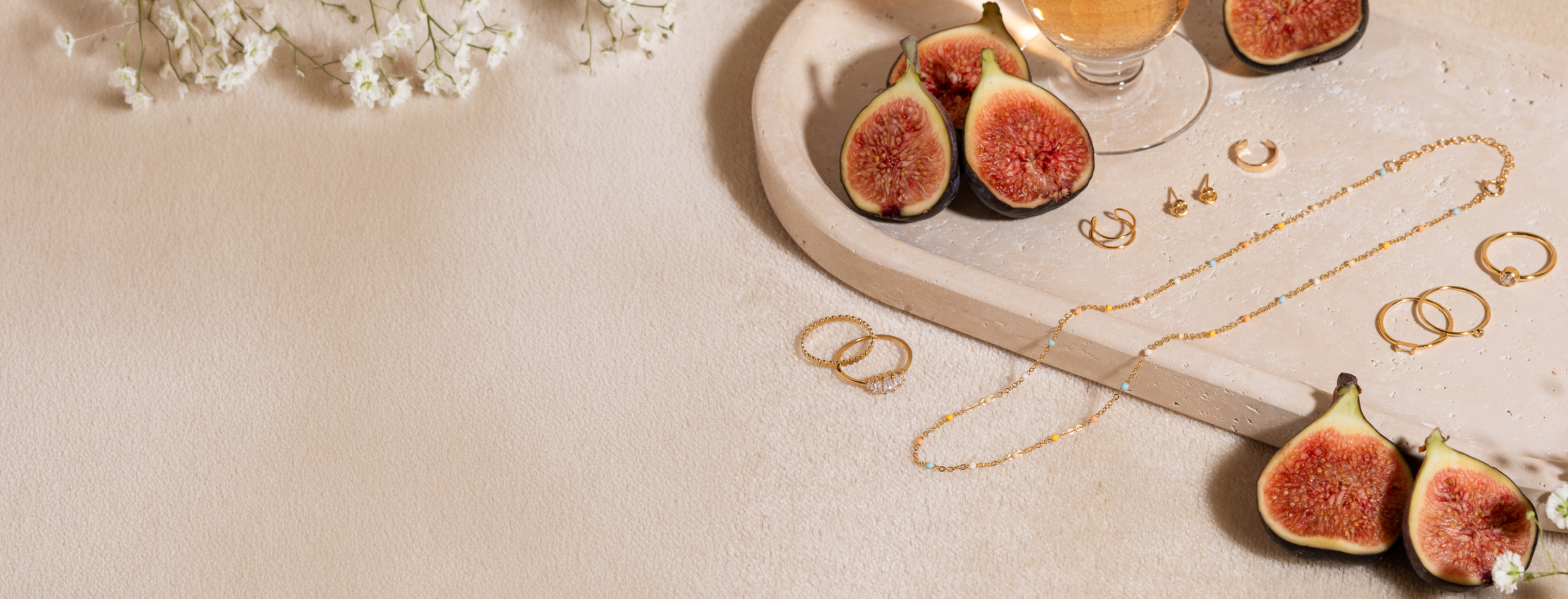 Sliced figs on a decorative plate with flowers and Dainty Enamel Pastel Chain and jewelry on a light background