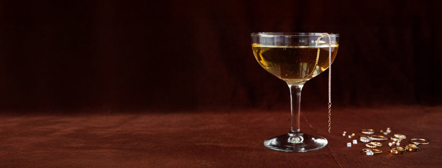 Champagne glasse with a burgundy background and jewelry