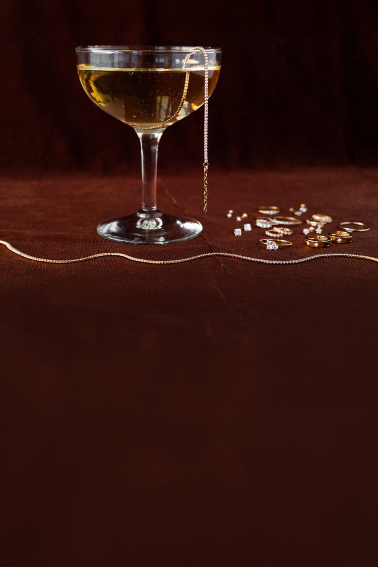 Champagne glasse with a burgundy background and jewelry