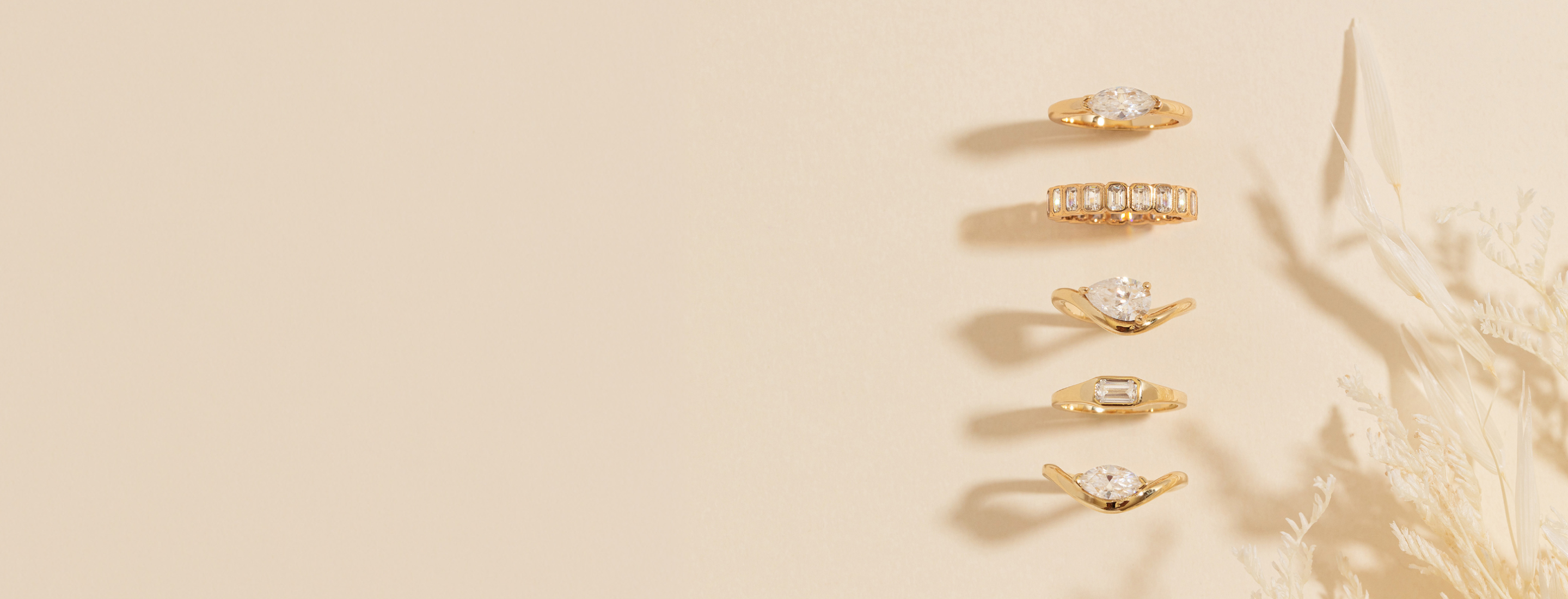 Set of gold pinky rings with mossanites on a beige background