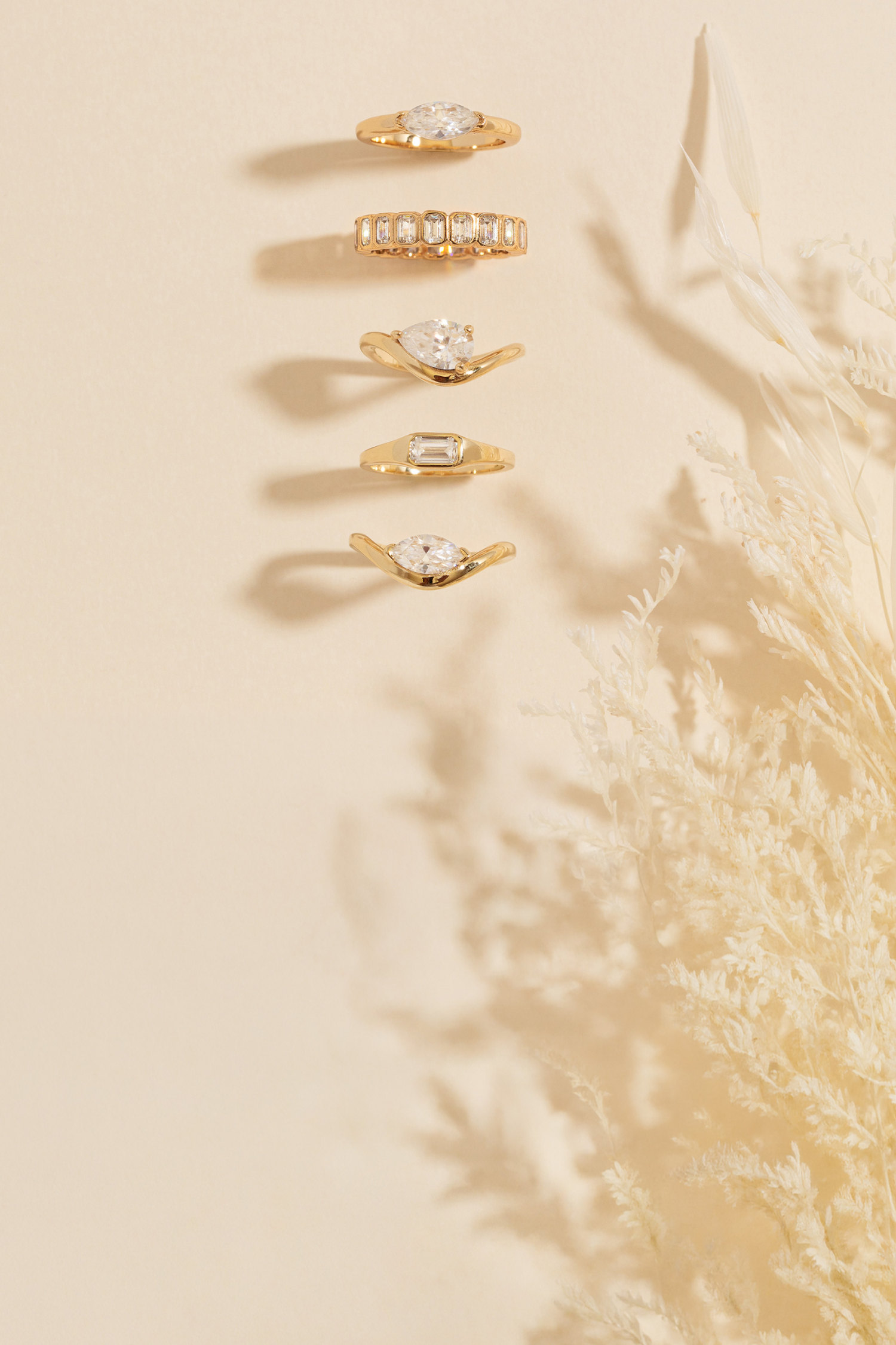 Set of gold pinky rings with mossanites on a beige background