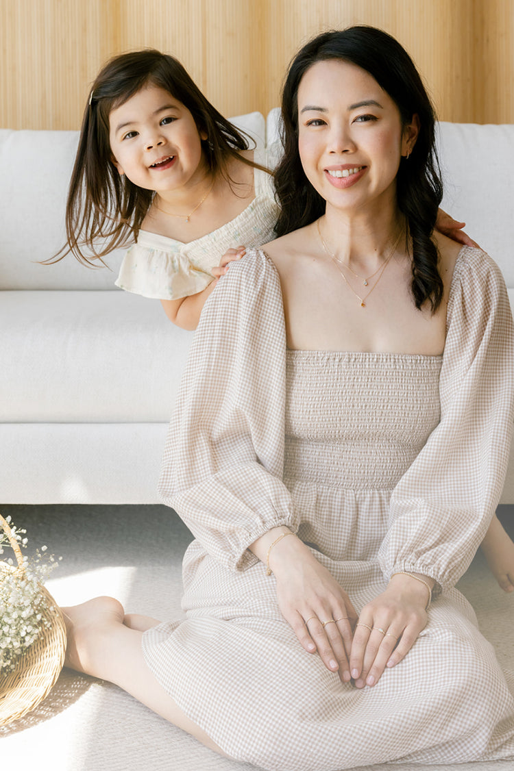 Mother and toddler daughter smiling while wearing matching necklaces