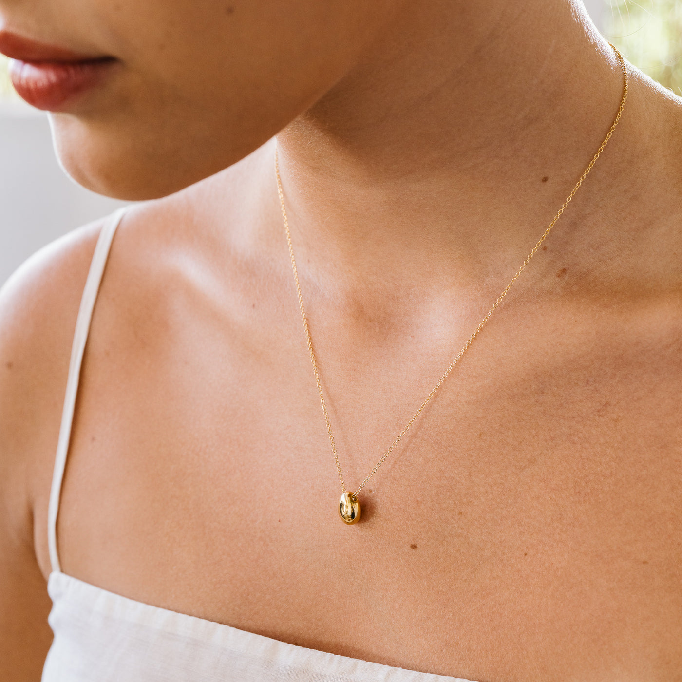 close up of woman's neck wearing pebble necklace