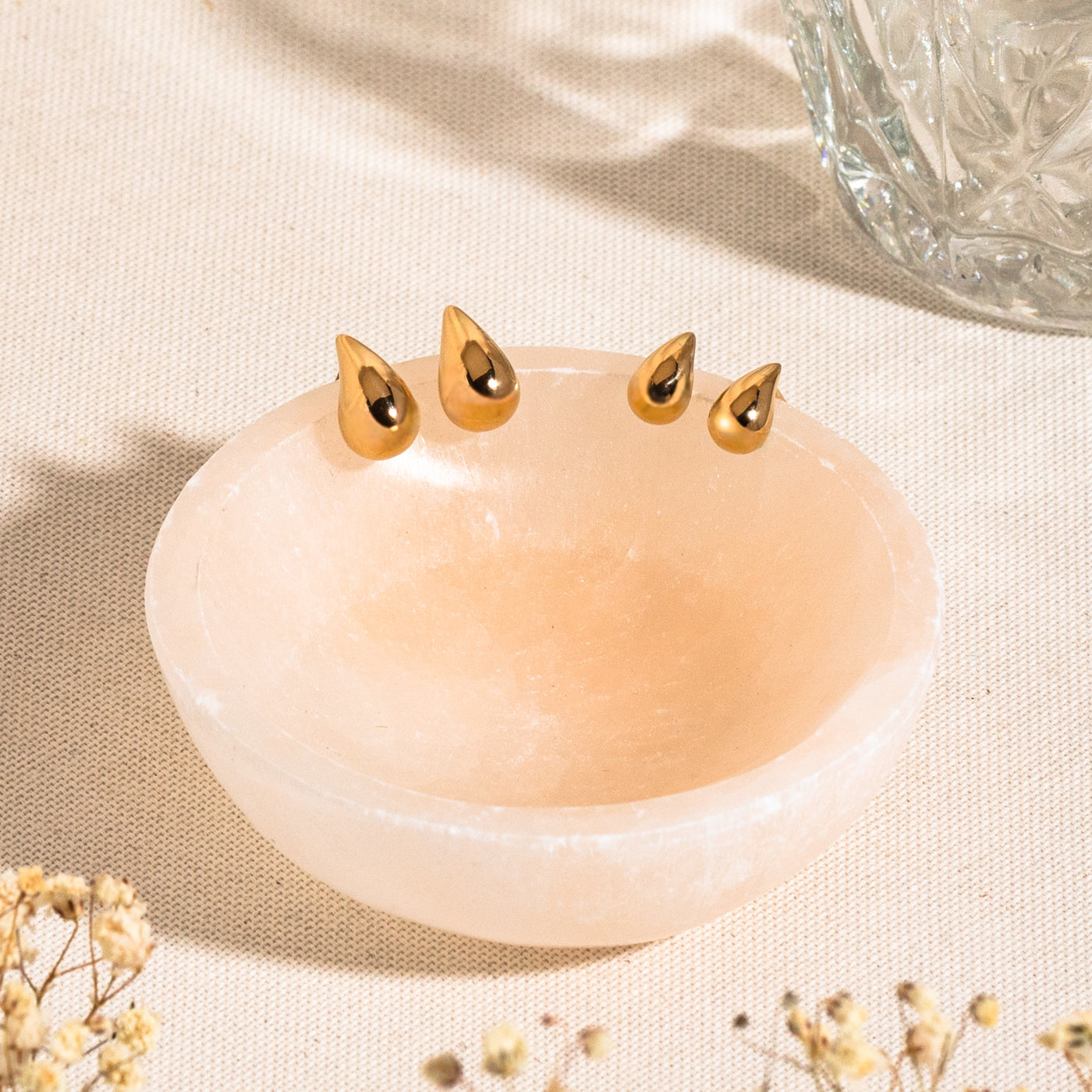 Small Large Teardrop Stud Earrings . 14k solid gold teardrop stud earrings and dainty teardrop stud earrings resting on the edge of a stone bowl.