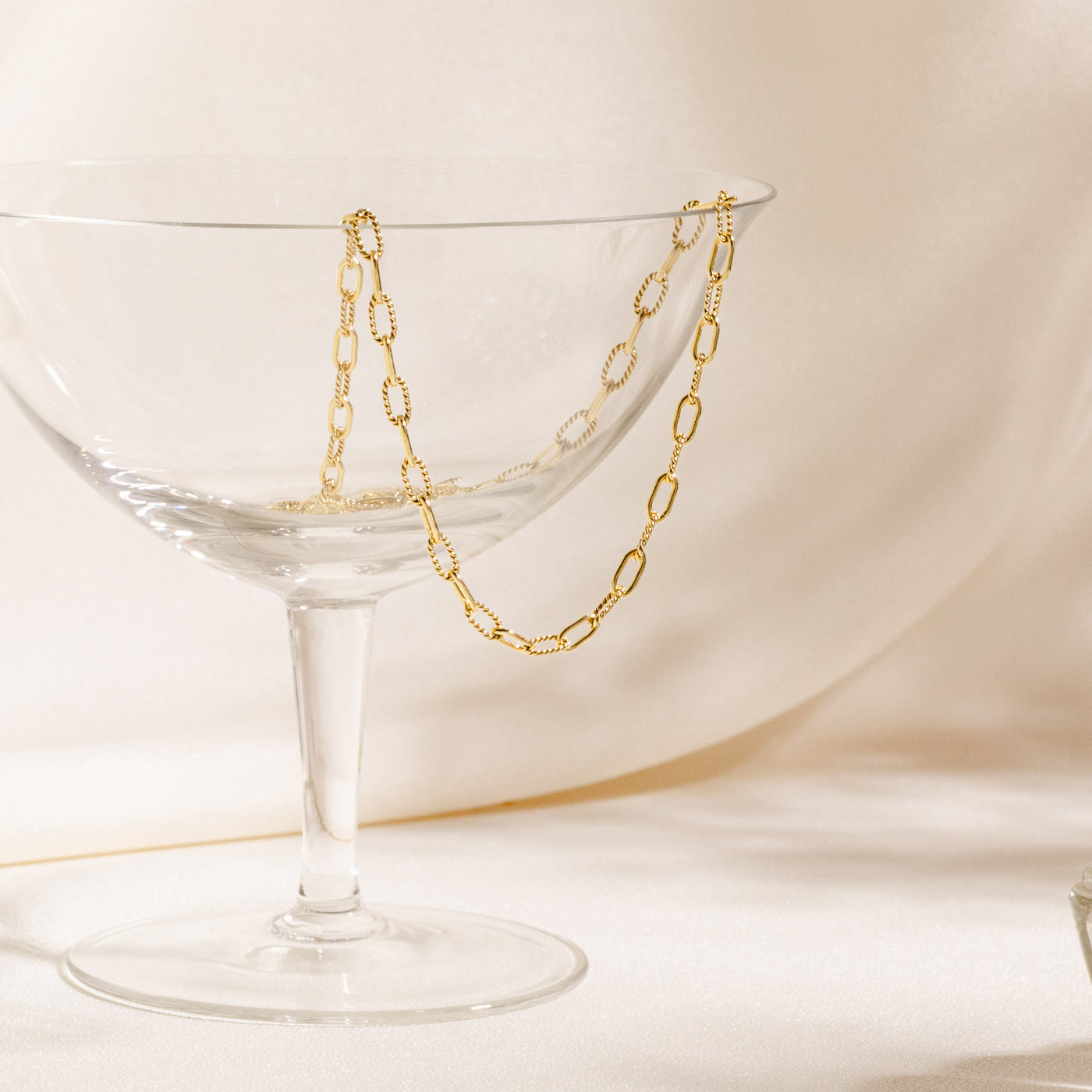 Glass cup with Twisted Paperclip Chain necklace hanging from it