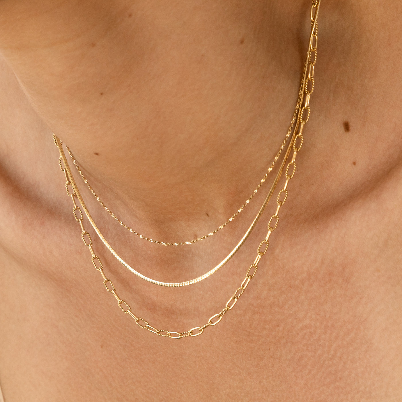Woman's neck with 3 chain necklaces hanging