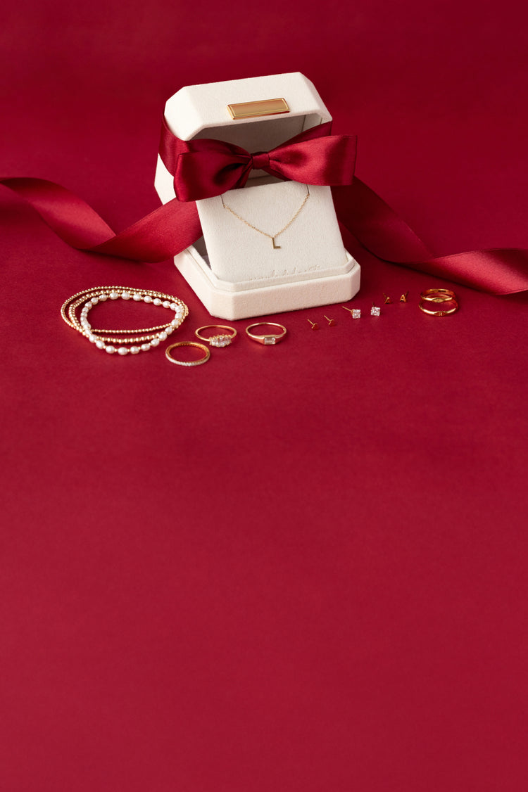 Jewelry box with a red ribbon and gold jewelry pieces on a red background